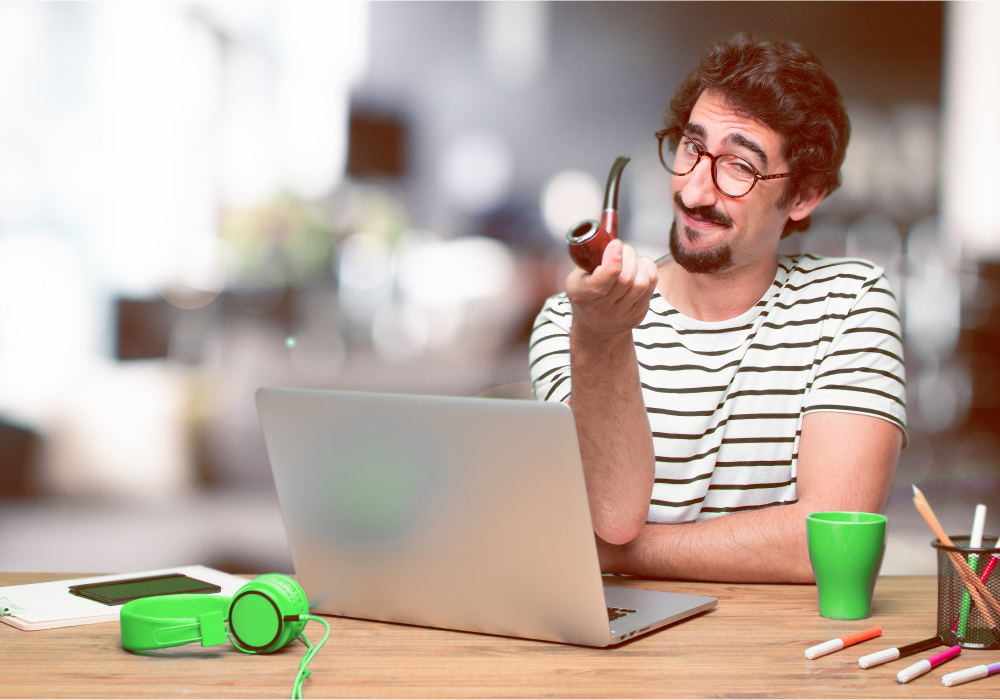 Man in striped top with a pipe sitting in front of laptop.